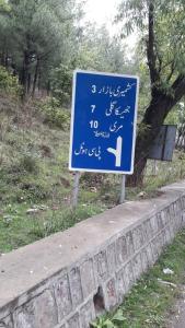 a blue sign on the side of a road at Green Valley Apartments in Bhurban