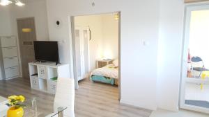 a white room with a bed and a television at Apartament Muszelka in Ustka