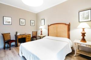 a bedroom with a white bed and a desk and a chair at Residenza Ognissanti in Florence