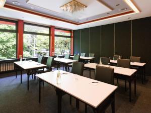 uma sala de jantar com mesas, cadeiras e janelas em DORMERO Hotel Freudenstadt em Freudenstadt