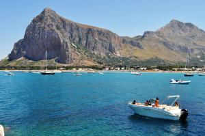a boat in the water with a mountain in the background at Villa I Due Pini in San Vito lo Capo