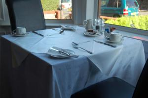 a table with a white table cloth and utensils on it at The Conifers in Edinburgh