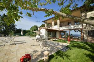 a house with a patio with chairs and a tree at Villa Clara in Assisi