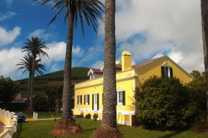 a yellow house with palm trees in front of it at Villa Várzea - Garden Suite in Várzea