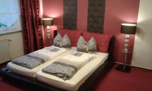 two beds in a red room with two lamps at Zum Holzwurm in Mühlanger