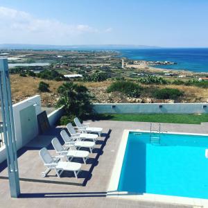 a pool with lounge chairs and a view of the ocean at B&B Torrefano in Portopalo