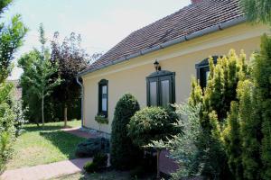 a house with bushes and trees in front of it at Rábagyarmati Apartman in Rábagyarmat
