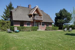 ein Haus mit einem Strohdach und Stühlen im Hof in der Unterkunft Haus Sonnenblume in Lohme