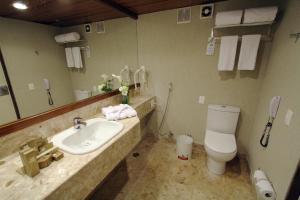 a bathroom with a toilet, sink, and mirror at Mar Hotel Conventions in Recife