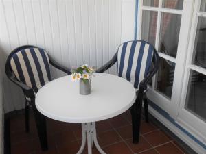 two chairs and a white table with a vase of flowers at Ferienwohnung-Moltrecht-2 in Laboe