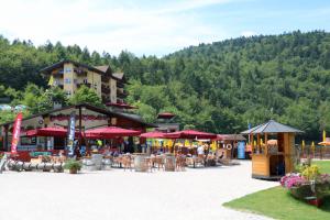 ein Resort mit Tischen und Sonnenschirmen auf einem Parkplatz in der Unterkunft Hotel Al Lago in Lavarone