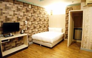 Habitación de hotel con cama y TV en Flower Motel, en Chiayi