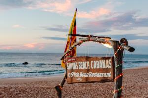 un cartel en la playa con una bandera en Shiva's Beach Cabanas, en Tangalle