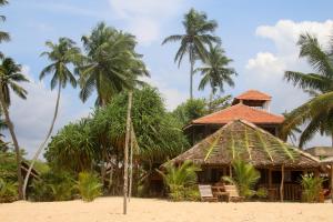 un complejo en la playa con palmeras en Shiva's Beach Cabanas, en Tangalle