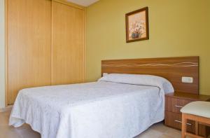 sypialnia z białym łóżkiem i drewnianym zagłówkiem w obiekcie Sanxenxorural - Apartamentos La Rana w mieście Sanxenxo