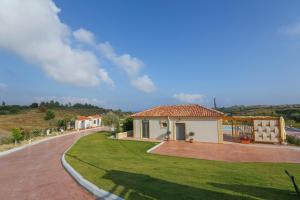 a house with a green lawn next to a road at Ameadros Resort in Mantzavináta