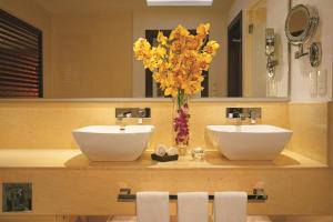 un baño con 2 lavabos y un jarrón de flores amarillas en Secrets Playa Mujeres Golf & Spa Resort - All Inclusive Adults Only en Cancún