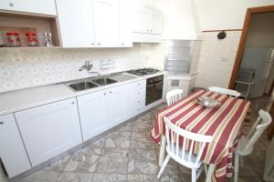 ガリポリにあるAppartamento bouganvilleのキッチン(白いキャビネット、テーブル、シンク付)