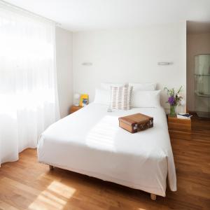 a white bed with a suitcase on top of it at Hôtel La Pérouse in Nantes