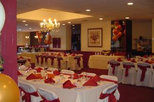 una sala de banquetes con mesas blancas y servilletas rojas en Ramada by Wyndham Watertown Thousand, en Watertown