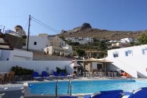 una piscina con sillas azules, mesas y edificios en Nikis Studios, en Panteli