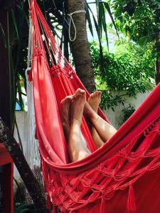 a man laying in a hammock under a tree at Pousada Atlantis in Jericoacoara