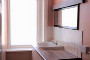 a bathroom with a sink and a mirror and a window at Foxhall Village Guest House in Blackpool