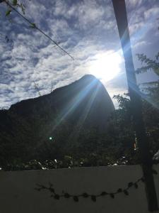 uma vista para uma montanha com o sol brilhando sobre ela em Riva's no Rio de Janeiro