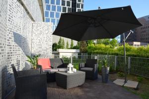 eine Terrasse mit einem Sonnenschirm, Stühlen und einem Tisch in der Unterkunft Apartamenty Oxygen DeLux in Warschau