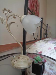 una lampada seduta su un tavolo accanto a un letto di Affittacamere La Camelia a Lucca