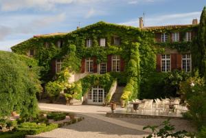 a building covered in ivy with tables and chairs at Château de Floure - SPA et piscine extérieure chauffée in Carcassonne