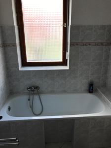 y baño con bañera y ventana. en Barátság Ház, en Alsóörs