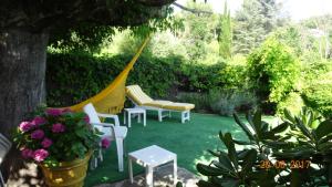a hammock in a garden with chairs and flowers at La maisonnette in Crillon-le-Brave