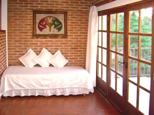 1 dormitorio con cama y pared de ladrillo en Costa Serrana Apart Hotel en Mina Clavero