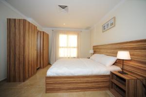 a bedroom with a large bed with a wooden headboard at Terrace Furnished Apartments- Salmiya in Kuwait