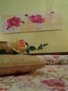 un letto con fiori sul muro accanto a un letto Sidx Sidx Sidx di Affittacamere La Camelia a Lucca