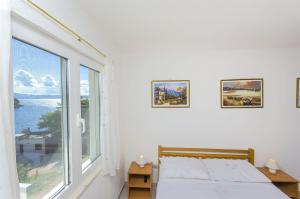 a white bedroom with a bed and a large window at Apartment Antonio in Bogomolje