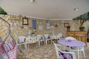 a room with tables and chairs and a stone wall at Room Milka in Veli Lošinj