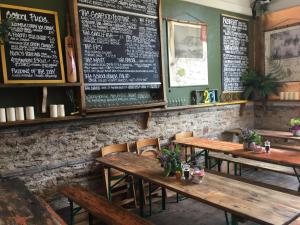 a restaurant with wooden tables and a menu on the wall at Pilchards Cottage in Noss Mayo