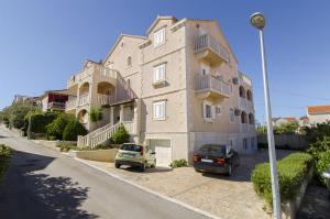 un grande edificio con auto parcheggiate di fronte di Apartments Mara a Supetar (San Pietro di Brazza)
