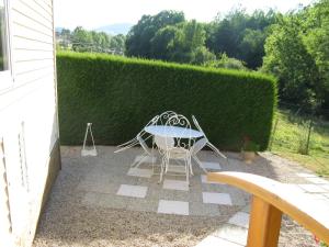 une terrasse avec une table, des chaises et une haie dans l'établissement Le Marverand, à Saint-Julien