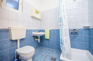 a blue tiled bathroom with a toilet and a sink at Apartments Nada in Rogoznica