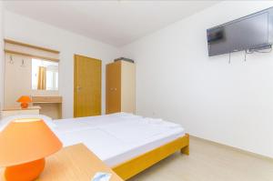 a bedroom with a bed and a tv on the wall at Apartments Tiho i Pave in Rogoznica