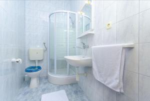 a white bathroom with a toilet and a sink at Apartments Tiho i Pave in Rogoznica