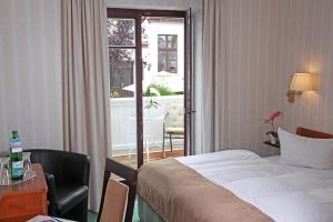a hotel room with a bed and a desk and a window at Hotel Doberaner Hof in Bad Doberan
