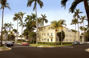 um grande edifício branco com palmeiras numa rua em The Brazilian Court Hotel em Palm Beach