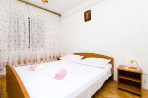una camera con 2 letti con lenzuola bianche e cuscini rosa di Apartments Ban a Dugi Rat (Punta Lunga)