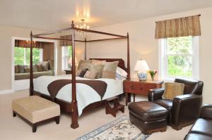 a bedroom with a canopy bed and a chair at 1795 Acorn Inn Bed and Breakfast in Canandaigua