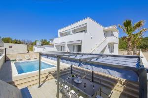 a villa with a swimming pool and a house at Apartments Villa V in Vir
