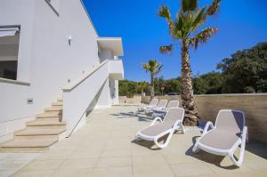 a row of lounge chairs on a patio with a palm tree at Apartments Villa V in Vir